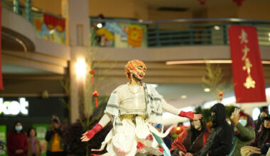A drag king performer dances in a crowded plaza.