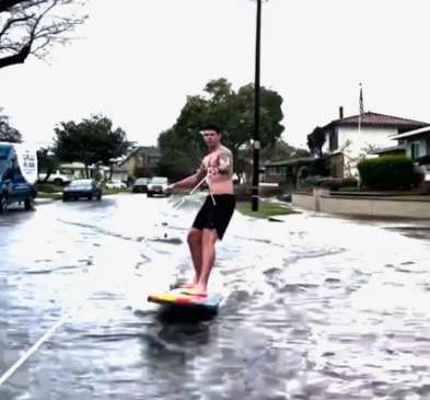 Hayden de Leon street surfing on a flooded Long Beach street.