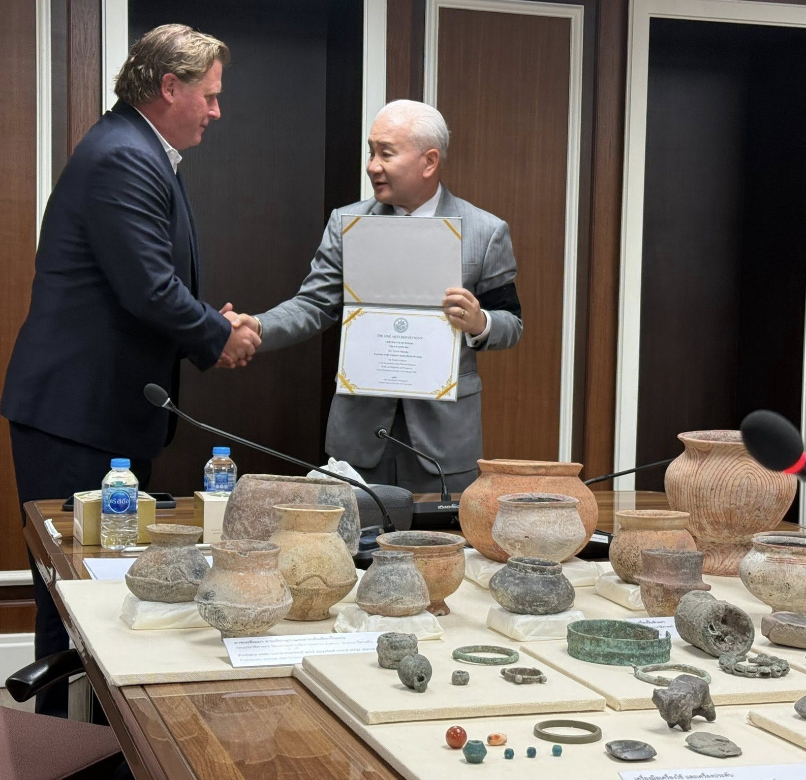 Trevor Murphy, left, shakes hands with Phnombootra Chandrajoti, director-general of...