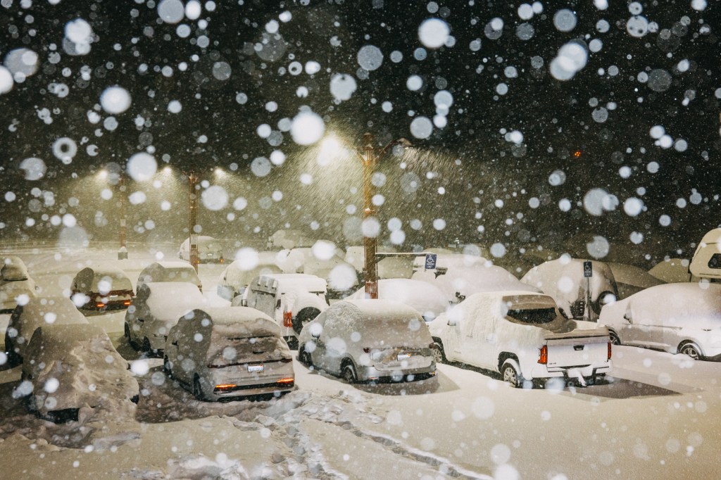 Heavy snowfall blankets cars and parking lot in Mammoth Lakes, California.