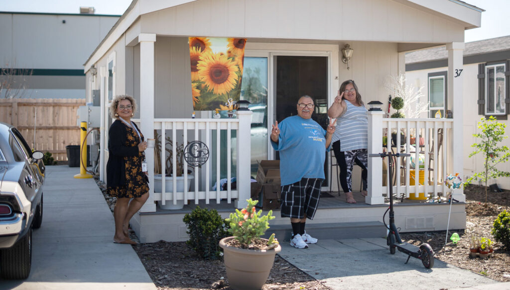 Neighbors give the peace sign while standing on their porch in the Salt + Light neighborhood.