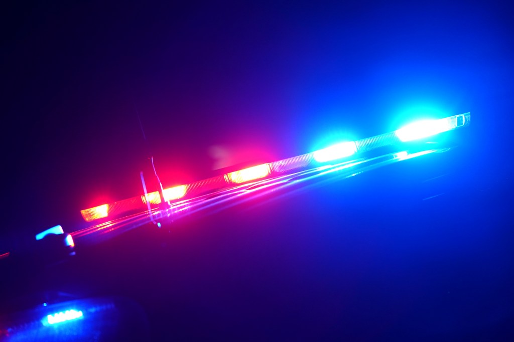 Police car emergency lights, red and blue, visible at night.