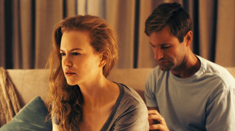 A woman sits with her back to a man as he touches her back