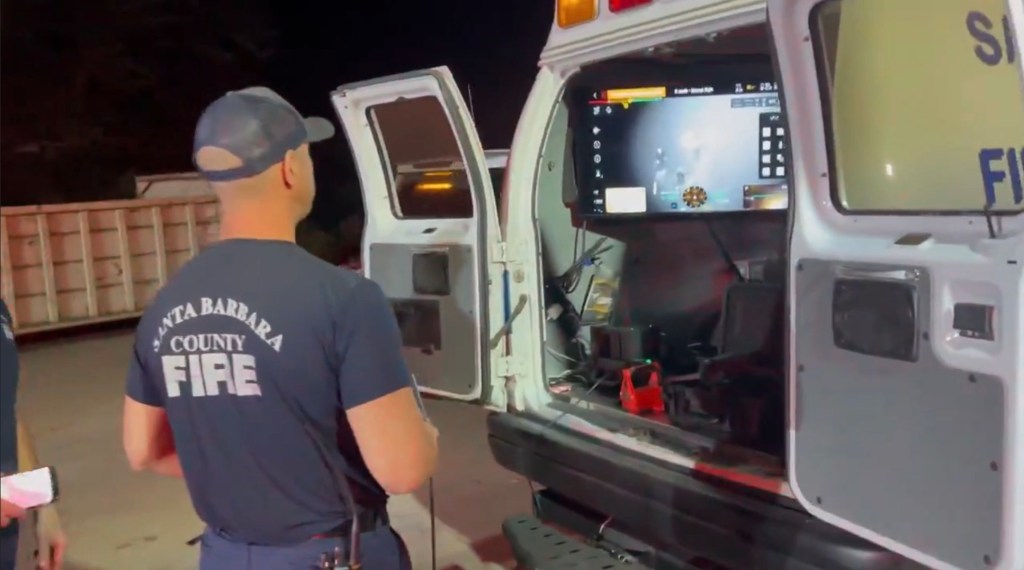 A Santa Barbara County Firefighter monitoring a drone on a screen in the back of an open vehicle.