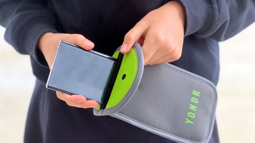 Image of a student putting a cellphone in a Yondr pouch