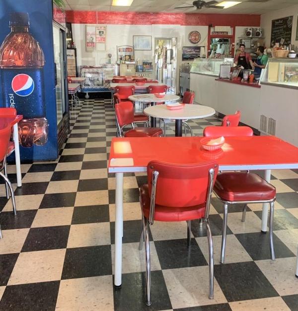 workers having a conversation behind the counter of a restaurant with red table sets