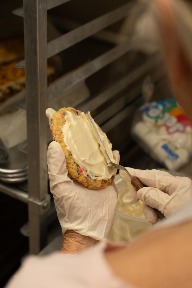 An employee frosts a Funfetti cookie at Schmackary's cookie shop, opening to the public on Saturday, Feb. 28, at 1255B University Ave., San Diego. (Jeromy Estabillo Chan/Slique Media)