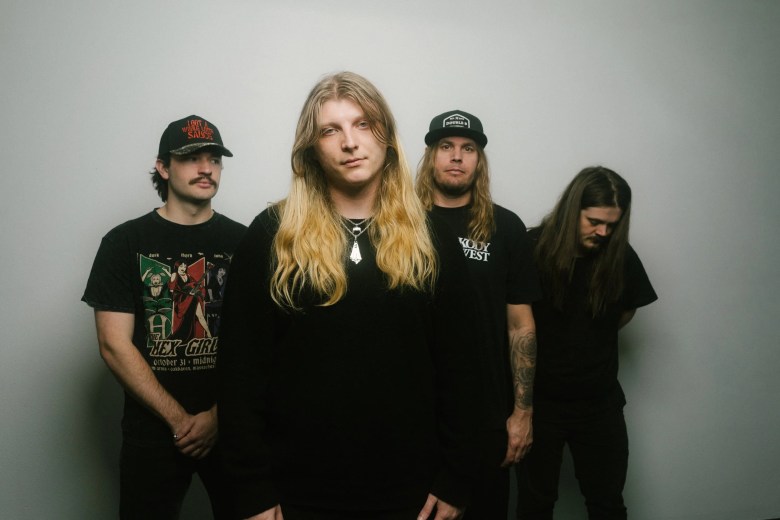 Four men dressed in black standing against a blank background