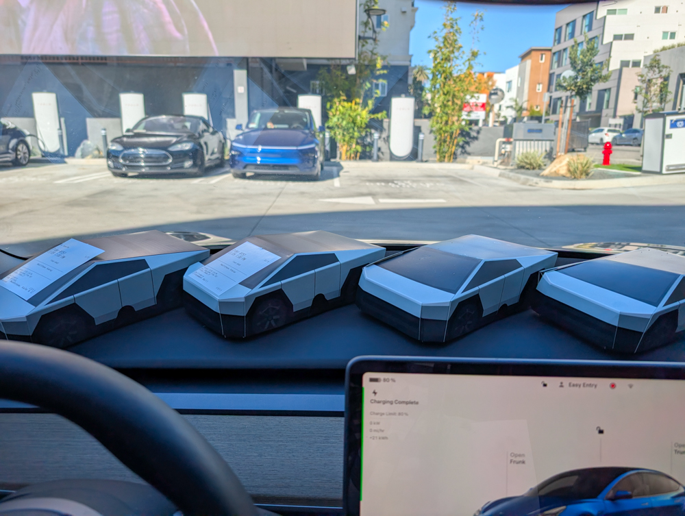 A lineup of Cybertruck shaped food boxes on a dashboard.