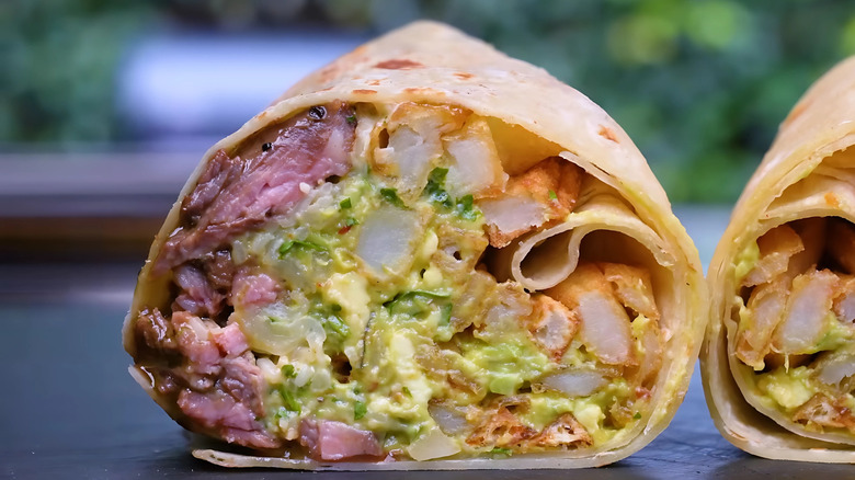 Cross-section of a Mission-style burrito with many fillings, wrapped in foil