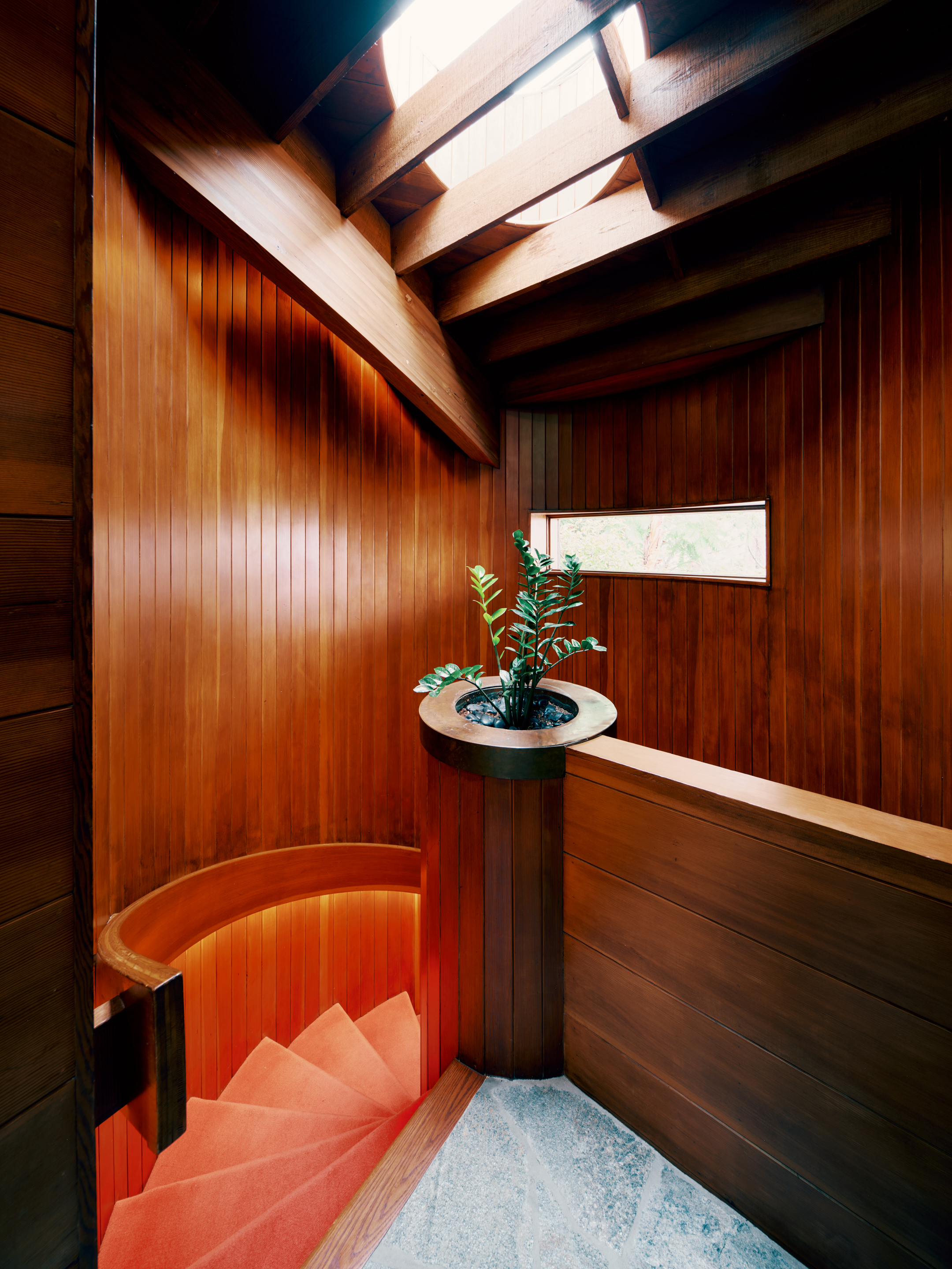 view of Lautner's Castle, a midcentury modernist house refreshed for the present day, showcasing arched timber, and stone and wood surfaces among greenery