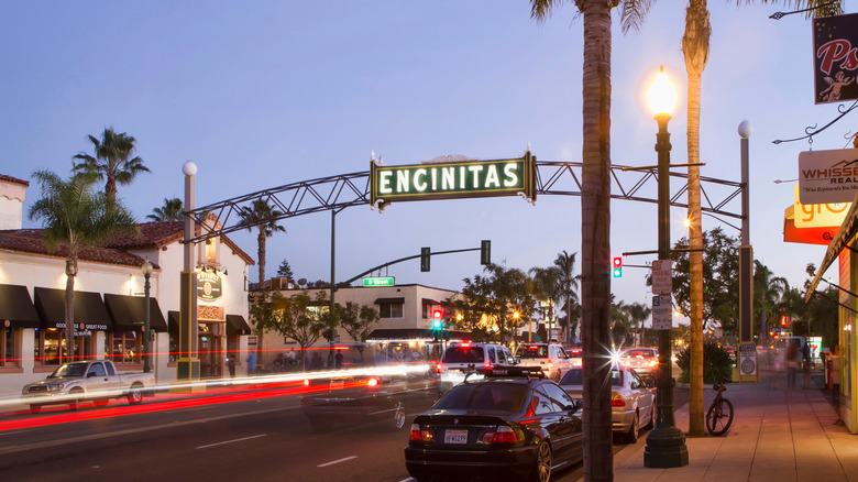 Evening in downtown Encinitas, California, with the iconic Encinitas archway above a palm-lined street