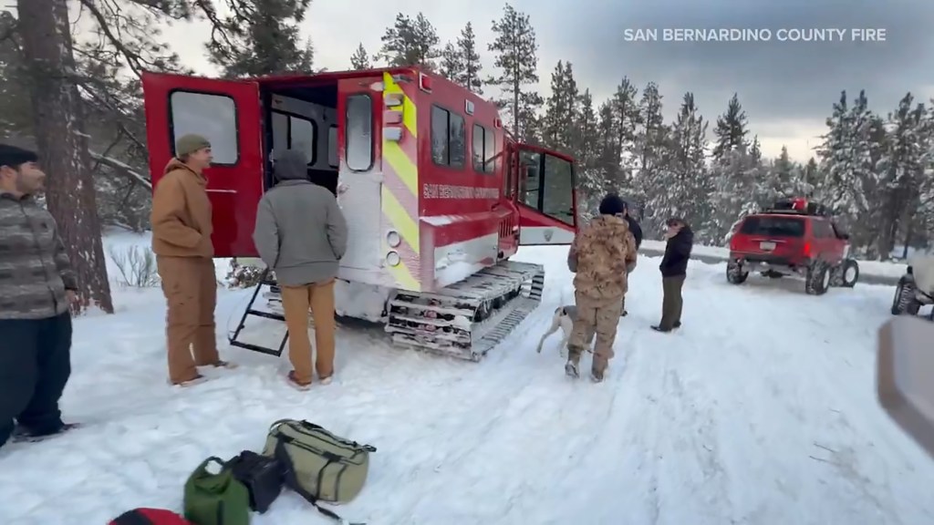 A snowcat and a rescue team extracting a stranded camper and his dog from a snow-covered valley.