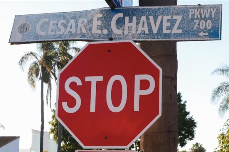 A stop sign in San Diego topped by a worn, bent and faded sign that reads "Cesar E. Chavez Parkway."