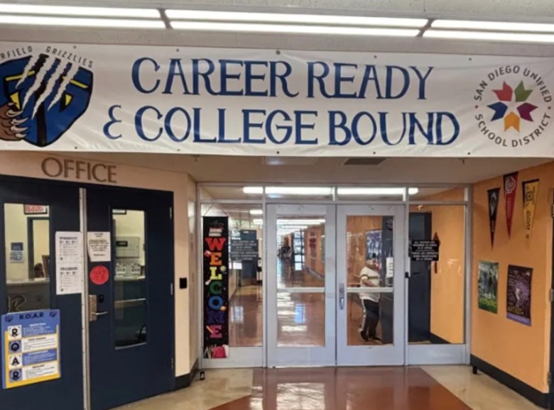 A banner with the words "Career Ready & College Bound" hangs over a school hallway with doorways leads to the main office.