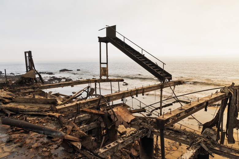 A black charred staircase remains standing one of amongst rubble of what used to be home overlooking the ocean.
