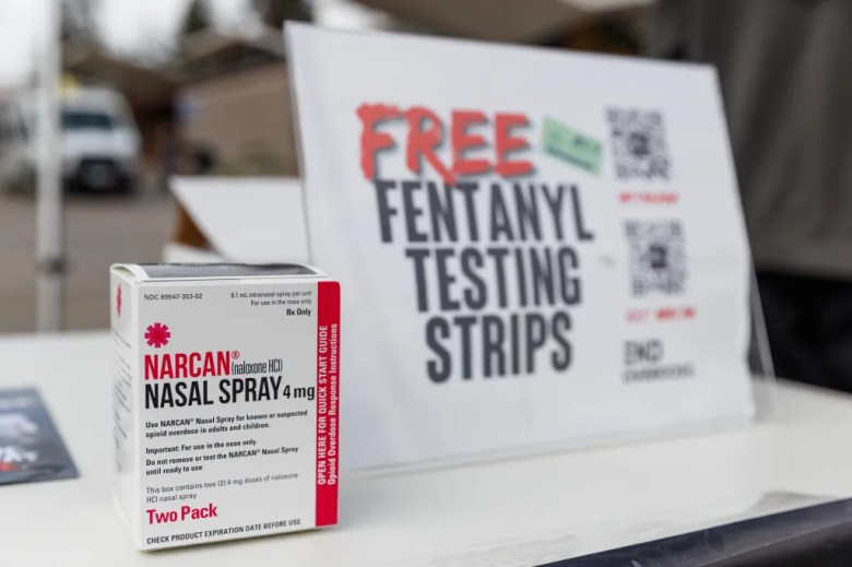 A box of Narcan nasal spray stands in front of a sign that reads "free fentanyl testing strips"