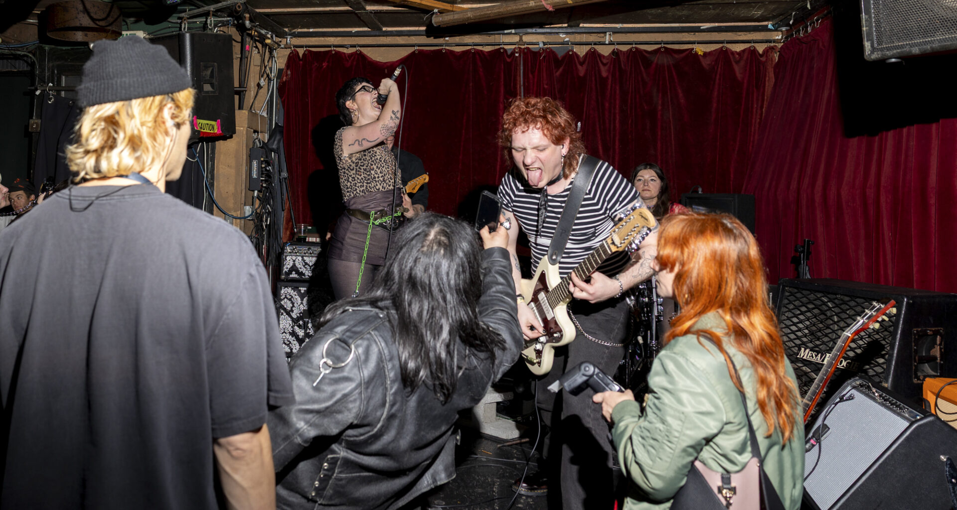 A young punk band plays on a dive bar's stage.