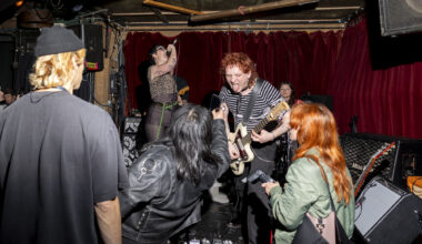 A young punk band plays on a dive bar's stage.