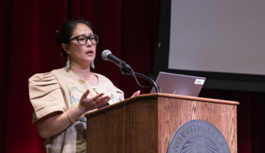 Maria Catrina Jaime speaks at a podium during the Global Health Consortium at the Oakland campus.