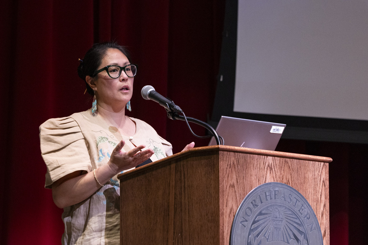 Maria Catrina Jaime speaks at a podium during the Global Health Consortium at the Oakland campus.