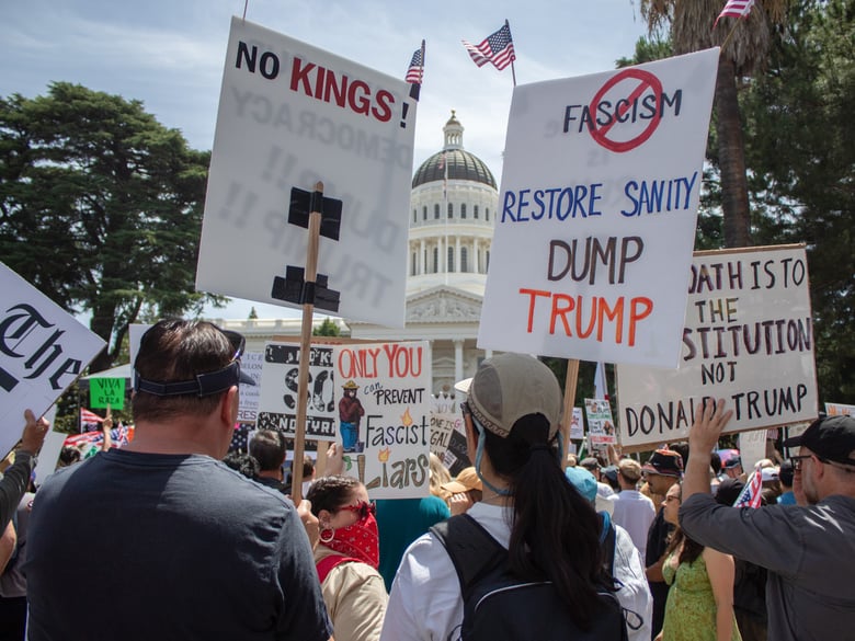 Protesters hold signs during the “No Kings” rally Saturday, June 14, 2025, outside of the California State Capitol at 1315 10th Street in Sacramento.