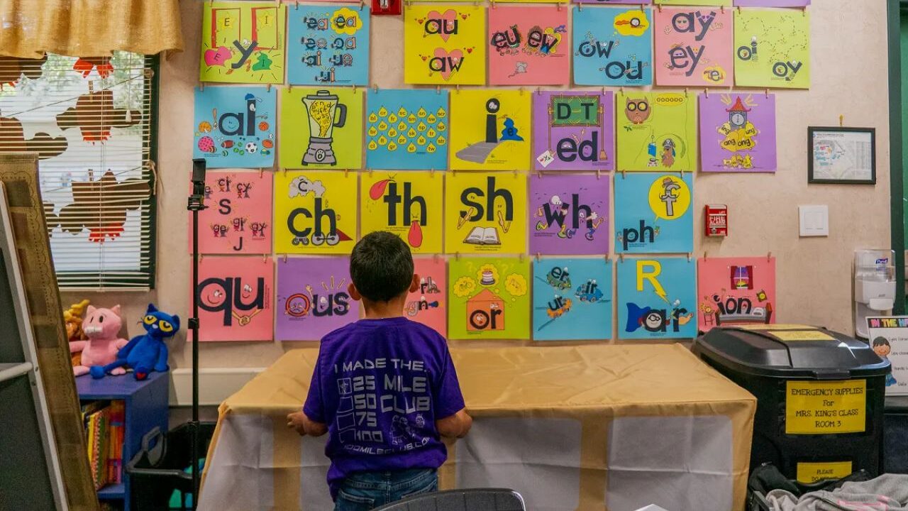 Image of a first-grader looking at a colorful phonetic alphabet on the all