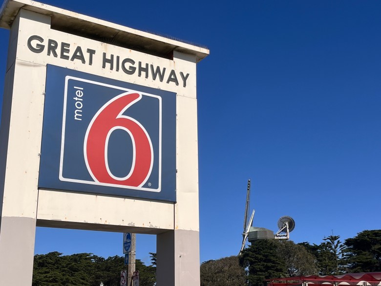 A motel 6 sign with an old wooden windmill in the background. 