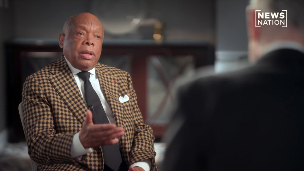 Man in a checkered jacket talking during an interview.