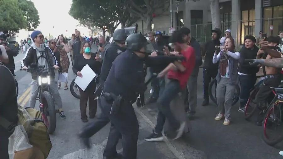 Officers detain protesters as mounted police and tactical units respond to clashes during the “No Kings” protest in downtown Los Angeles.