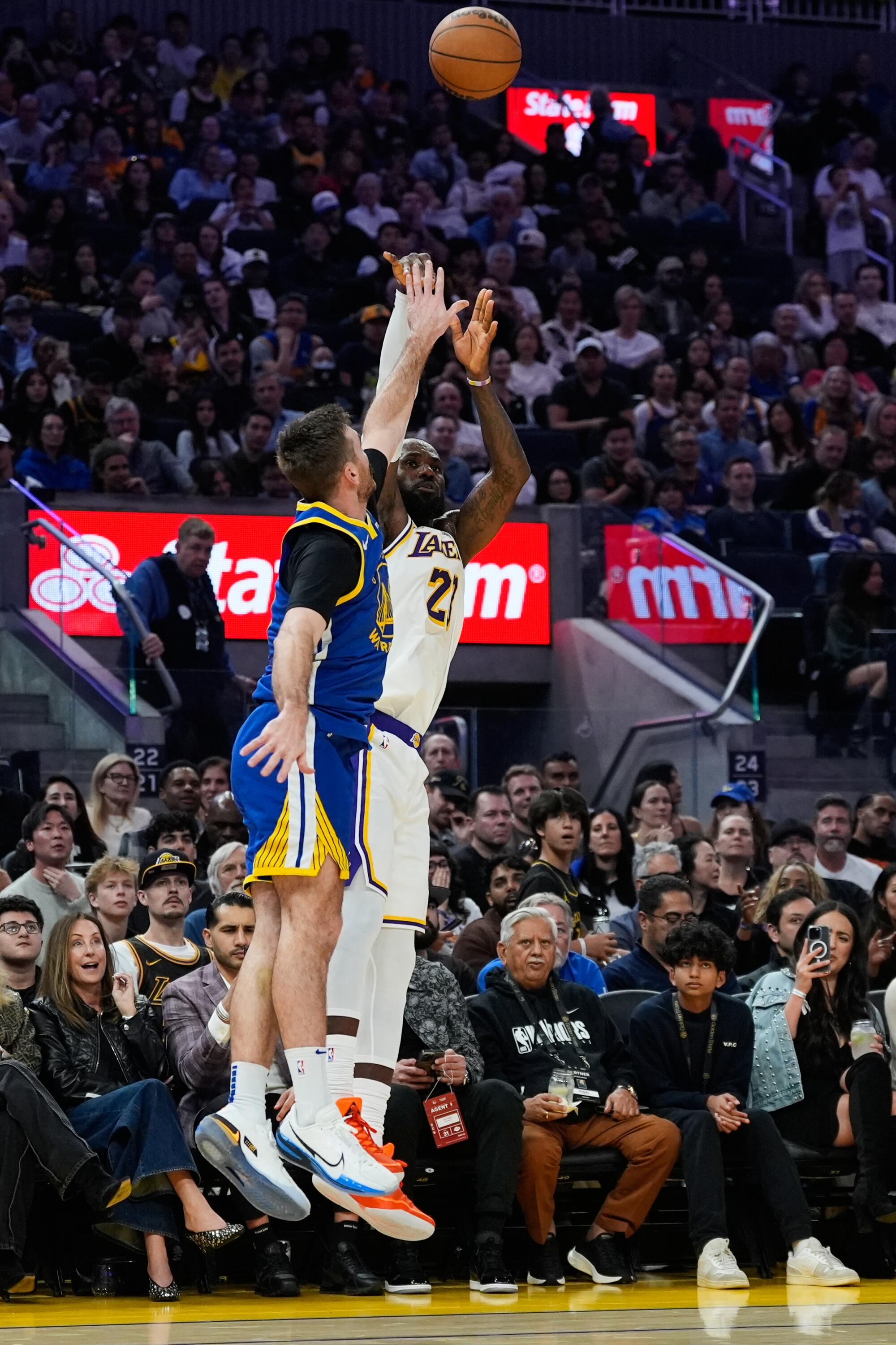 Lakers star LeBron James shoots a three-pointer over Golden State Warriors guard Pat Spencer in the first half Saturday.