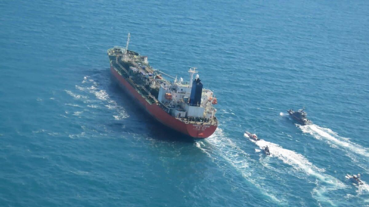 A seized South Korean-flagged tanker is escorted by Iranian Revolutionary Guard boats.