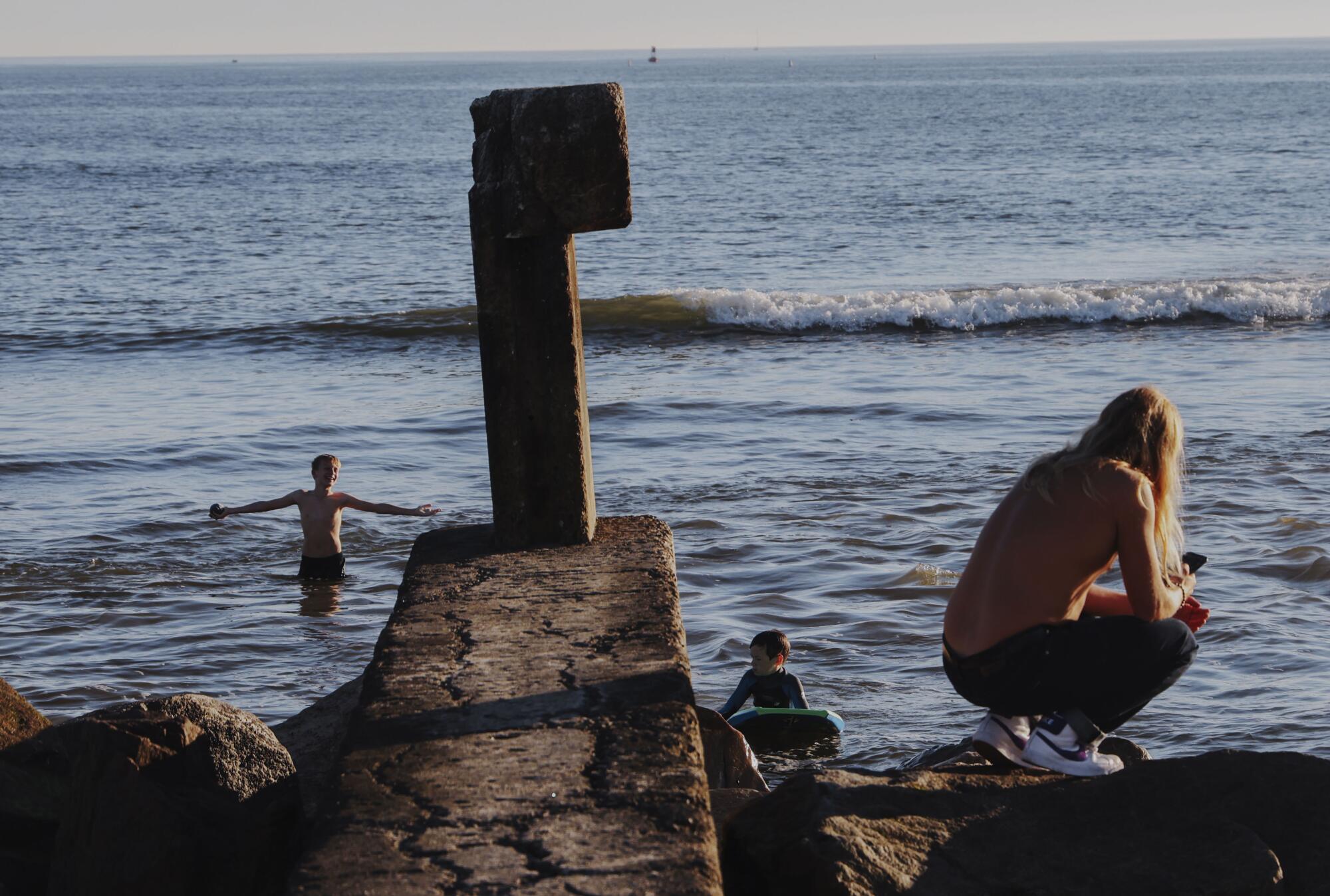 Beachgoers play in the water at the mouth of the San Juan Creek as it flows into the Pacific Ocean.