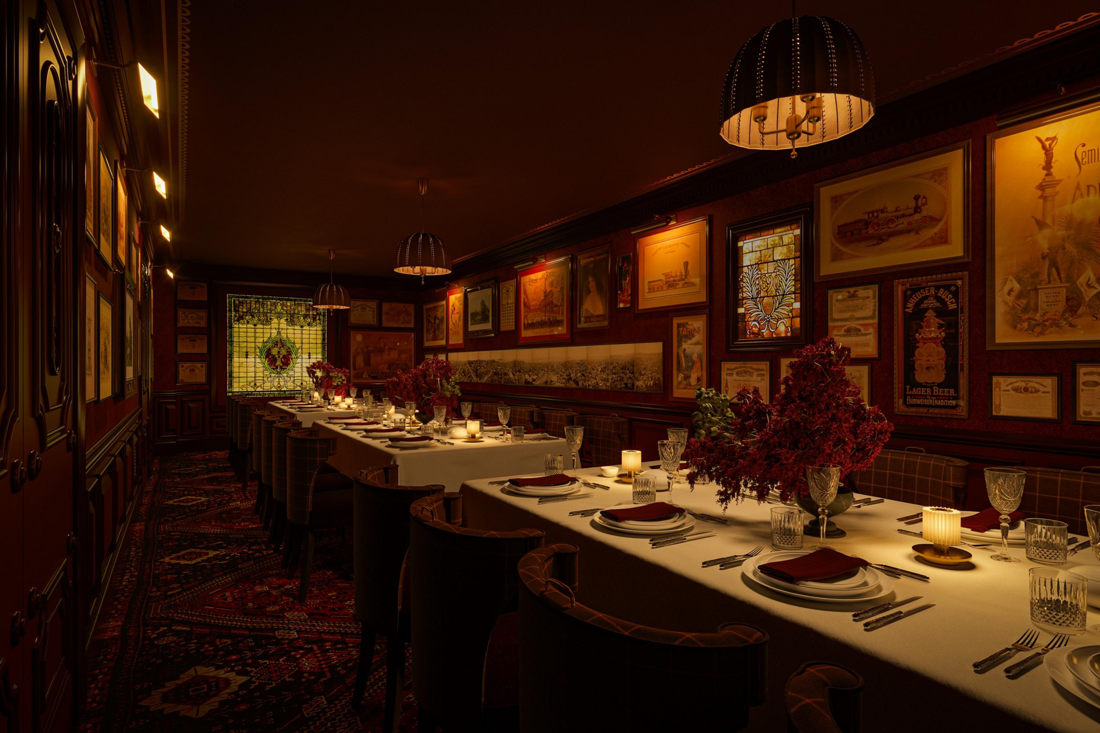 A dimly lit, elegant dining room features long tables with white linens, floral centerpieces, candles, and vintage framed artwork on dark wood-paneled walls.