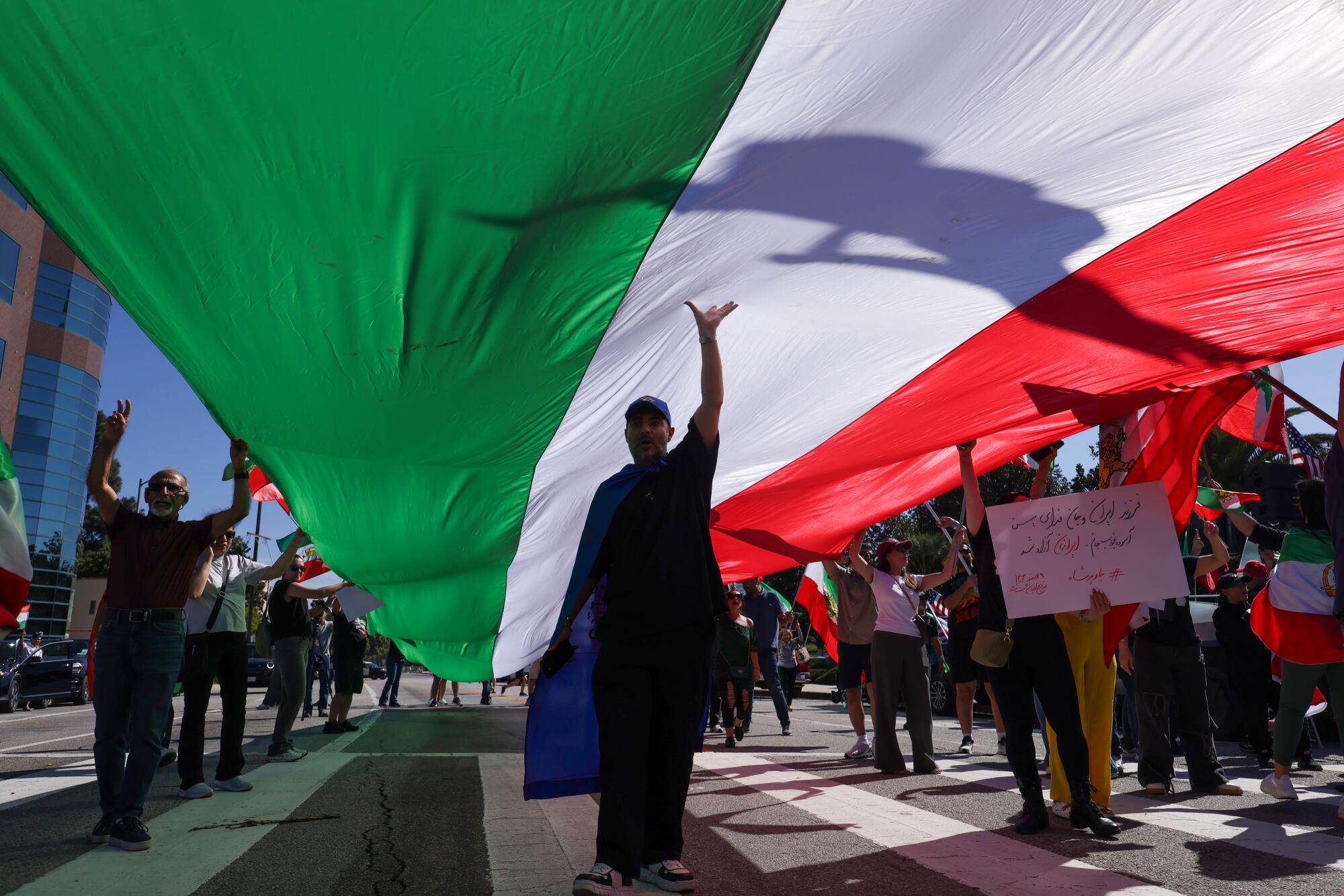 A man walks under a giant Iranian flag.
