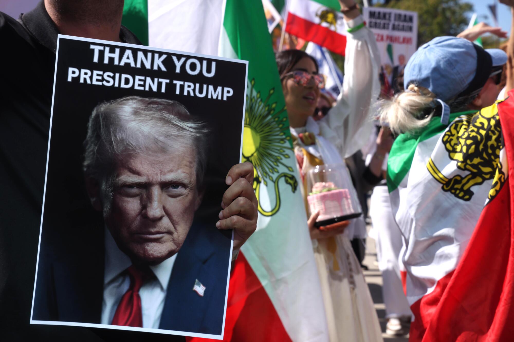 A person holds a poster with a photo of Trump and the message "Thank You President Trump."