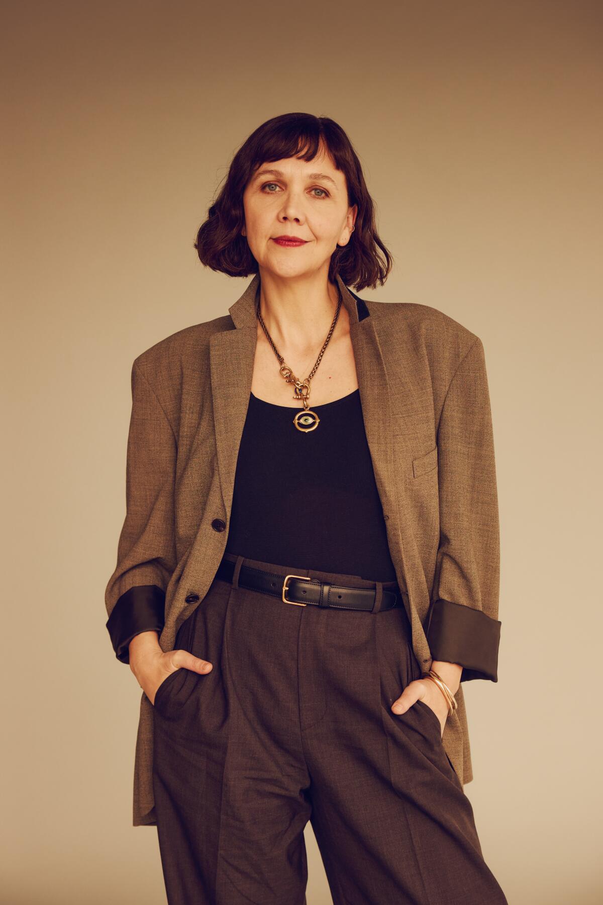 A woman in a blazer stands with her hands on her hips.