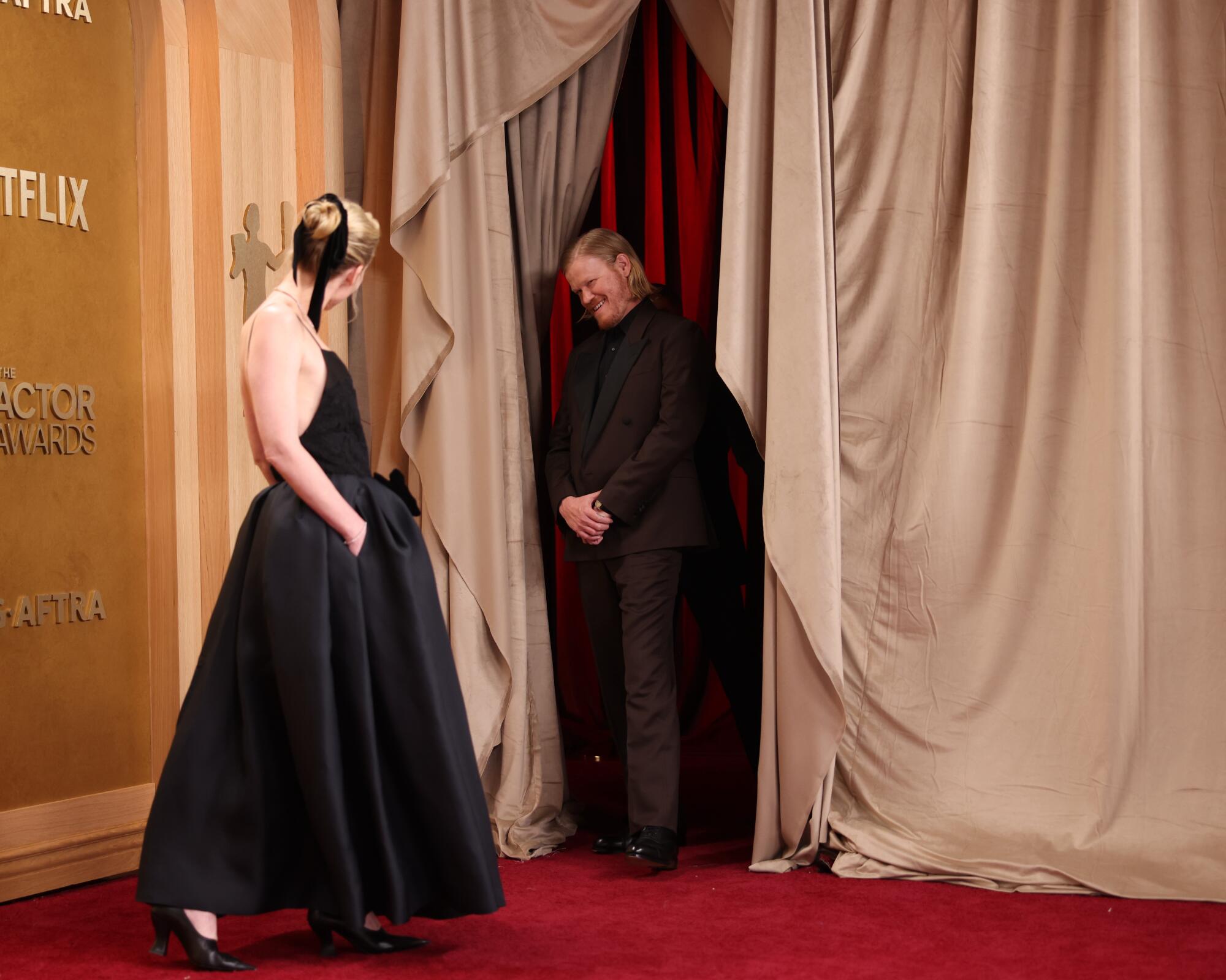 Kirsten Dunst and Jesse Plemons look at each other on the red carpet. 