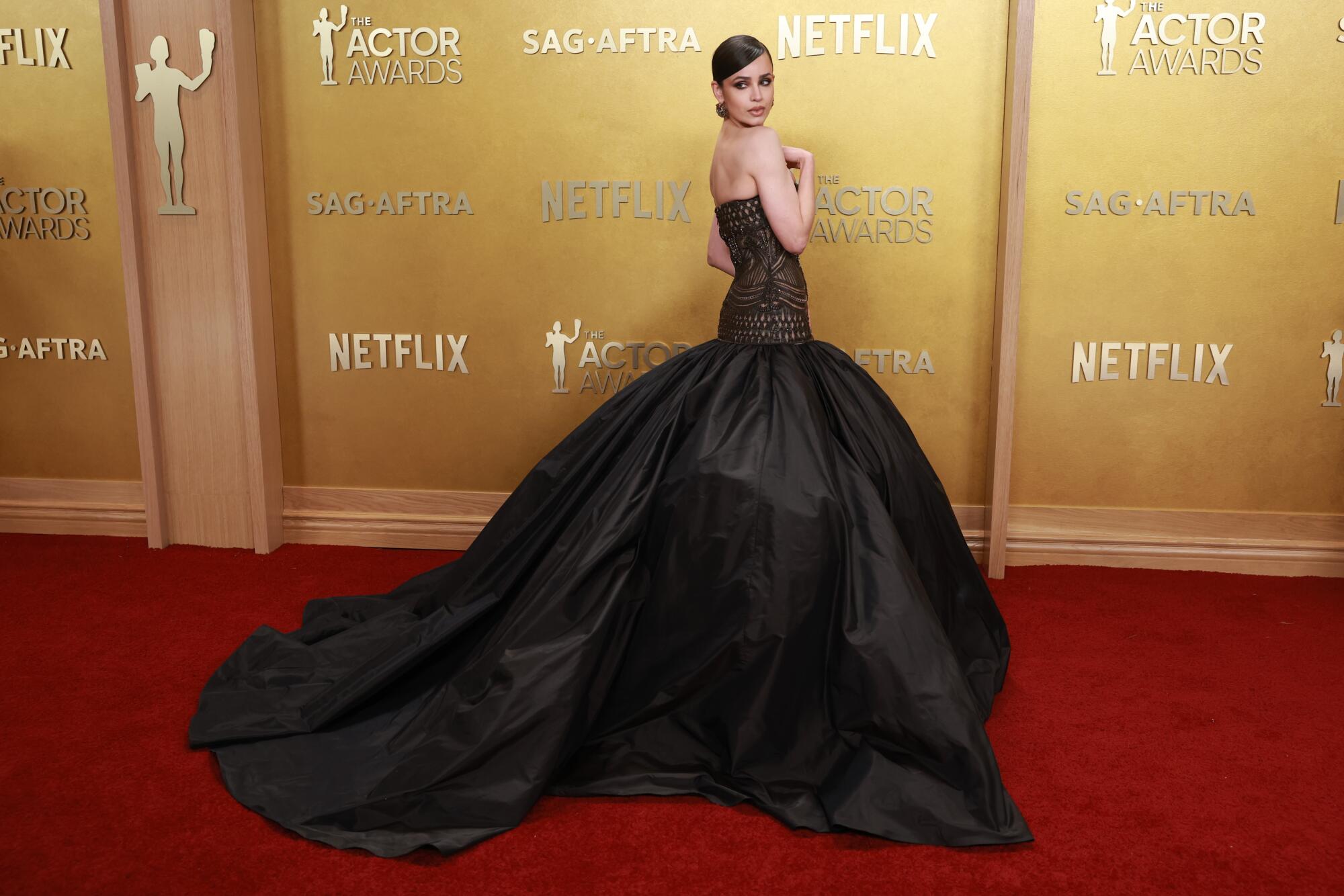 Sofia Carson, wearing a black ballgown, poses on the red carpet. 