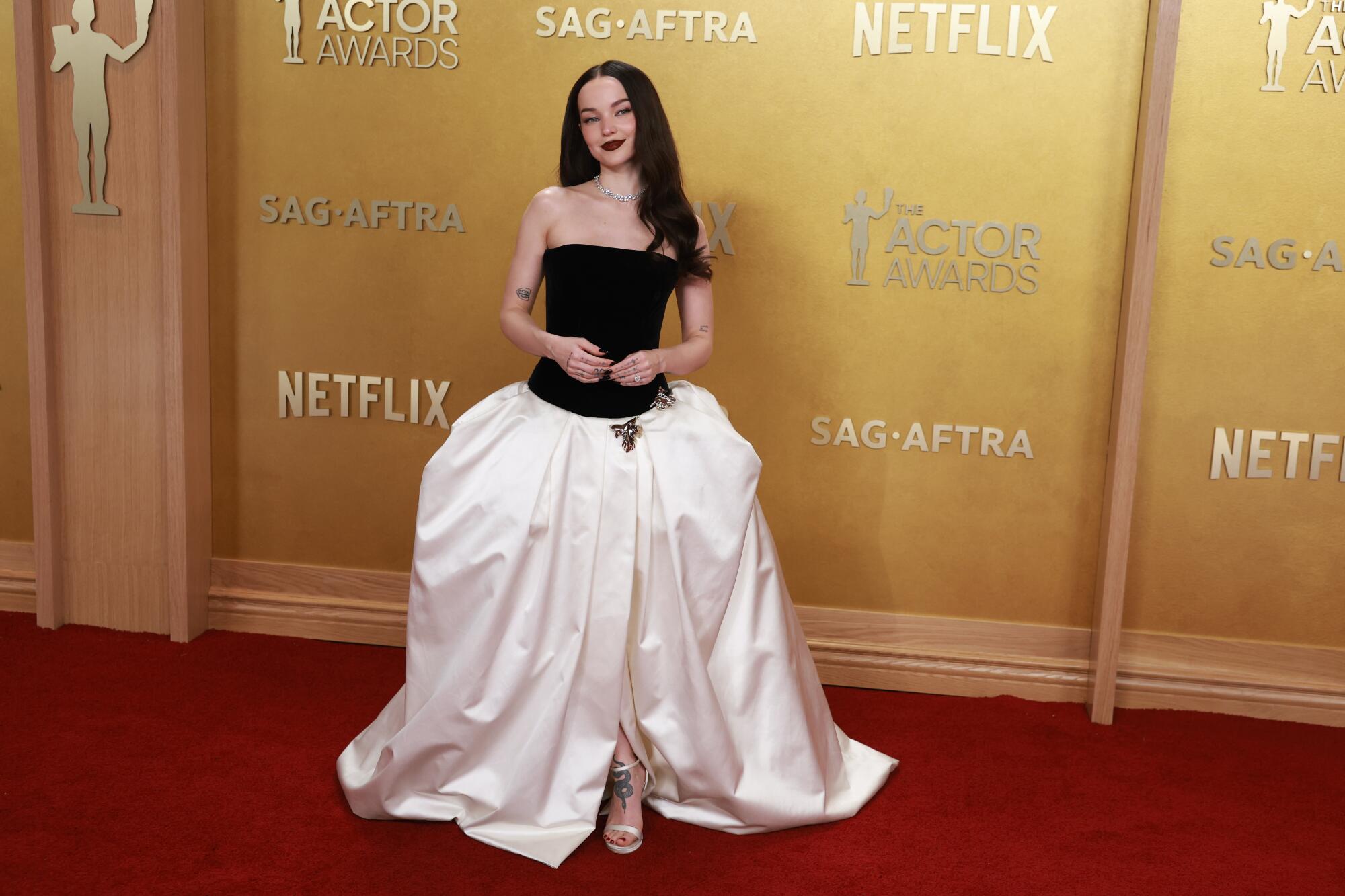 Dove Cameron, wearing a black and white ball gown, poses on the red carpet. 