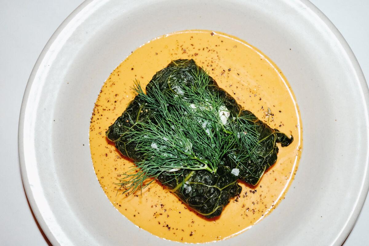 A bowl of two stuffed cabbage rolls with abalone rice atop  an orange-colored sauce at Little Fish in Melrose Hill.