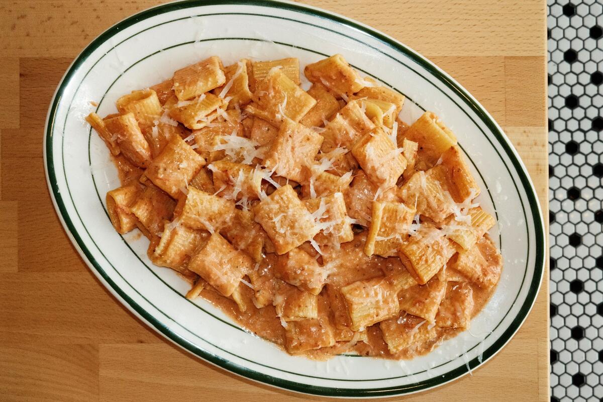 Anna Pizza's rigatoni in vodka sauce on a wood table above black-and-white patterned floor tile