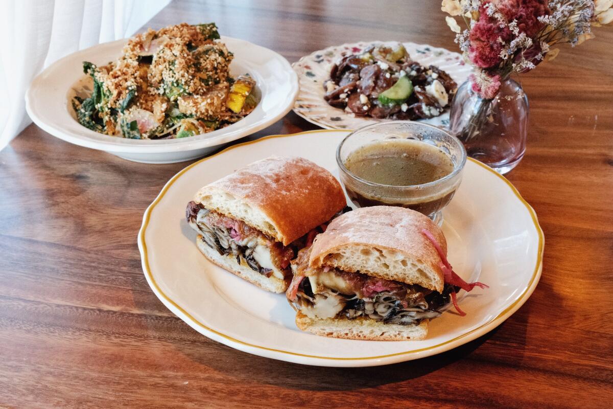 Two halves of a mushroom dip with heirloom bean salad and an avocado chopped salad on a wood table