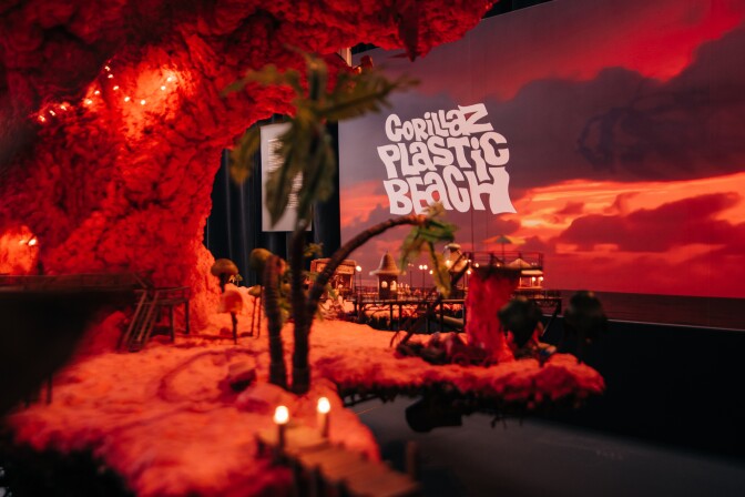 An art exhibit of a plastic beach scene with text on a screen reading "Gorillaz Plastic Beach"