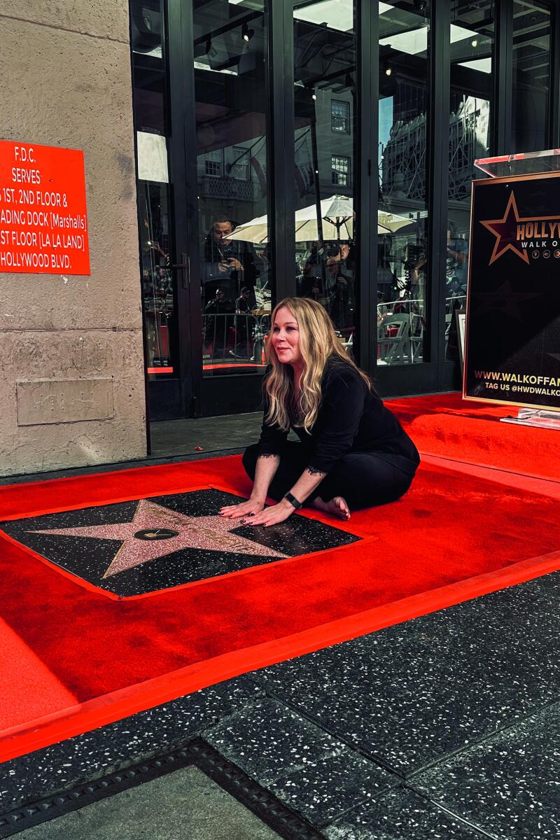 Christina Applegate sits next to a pink star on the Hollywood Walk of Fame.