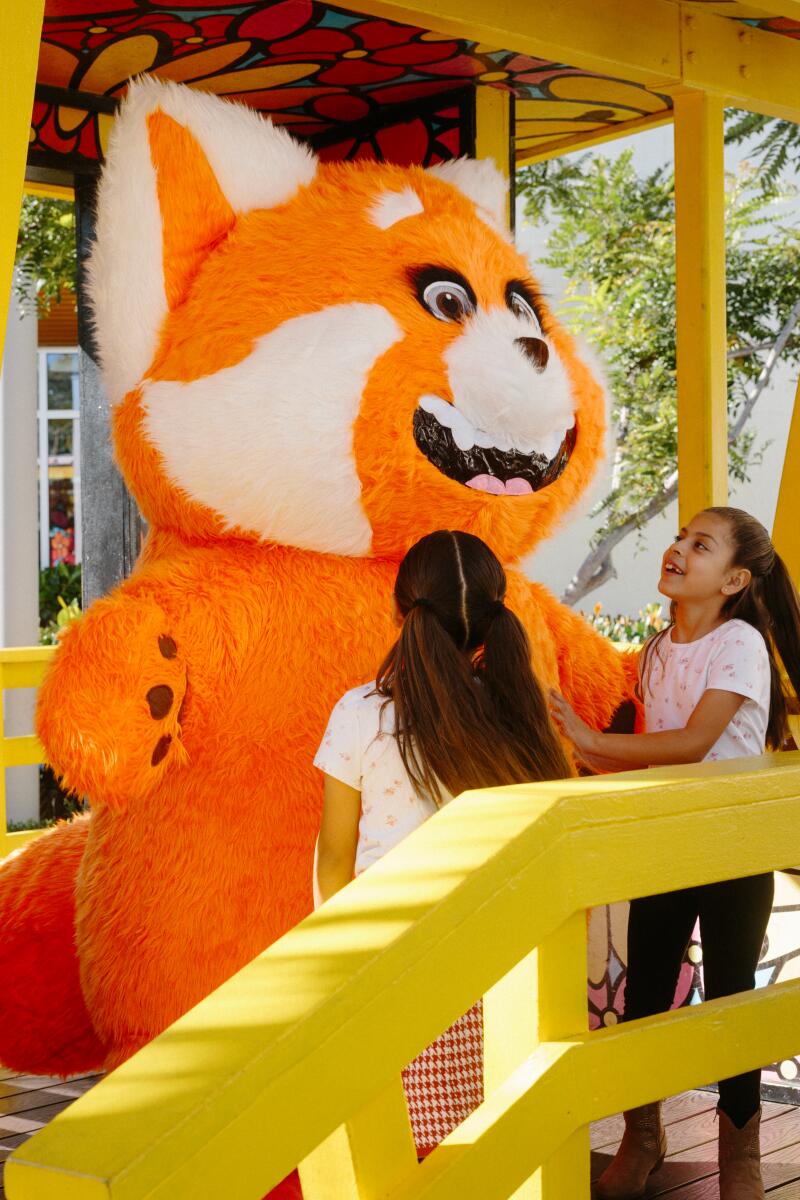 Twin sisters Emma and Ella Sandoval greet the character Mei Mei