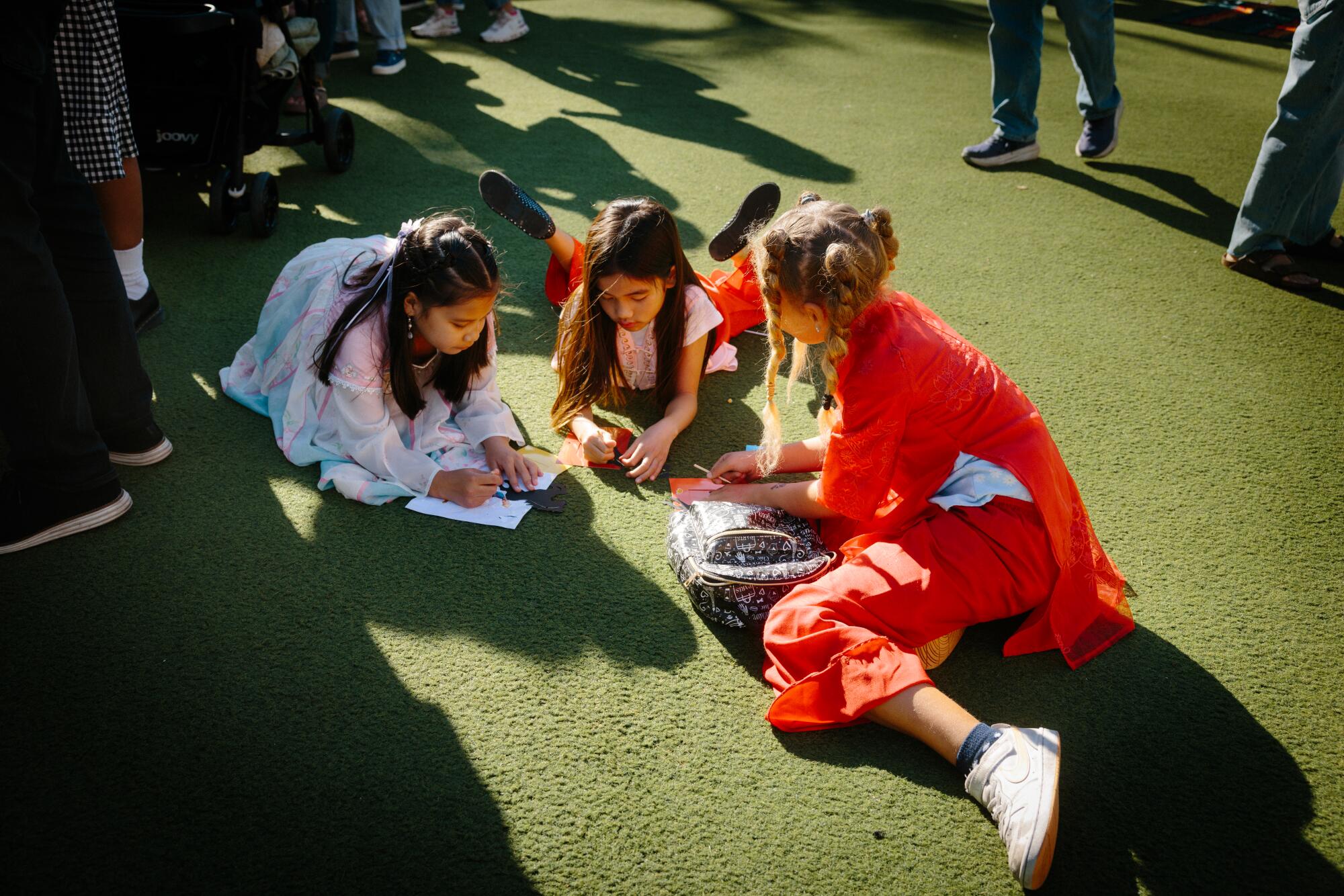 Three girls do craft activities on the lawn during the Lunar New Year celebration at The Point.