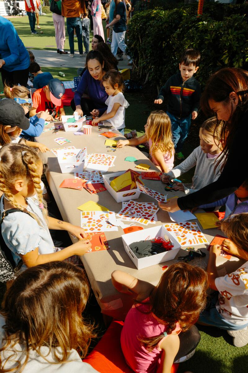 Twin sisters Emma and Ella Sandoval, left, greet the character Mei Mei at the Point during a Lunar New Year celebration. Kids and parents participate in craft activities at the celebration on Sunday, February 22, 2025.
