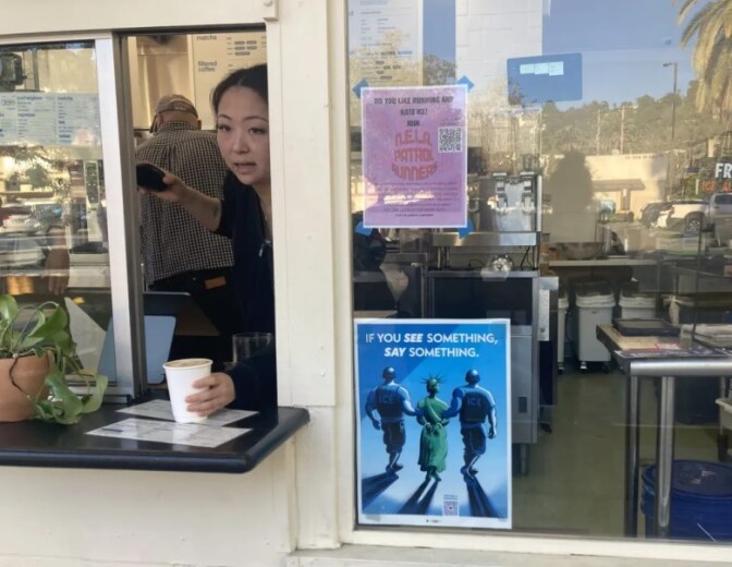 A flyer on the inside of a window reads "N.E.L.A. Patrol Runners" as a worker places a cup of coffee on the small through through a window next to it.