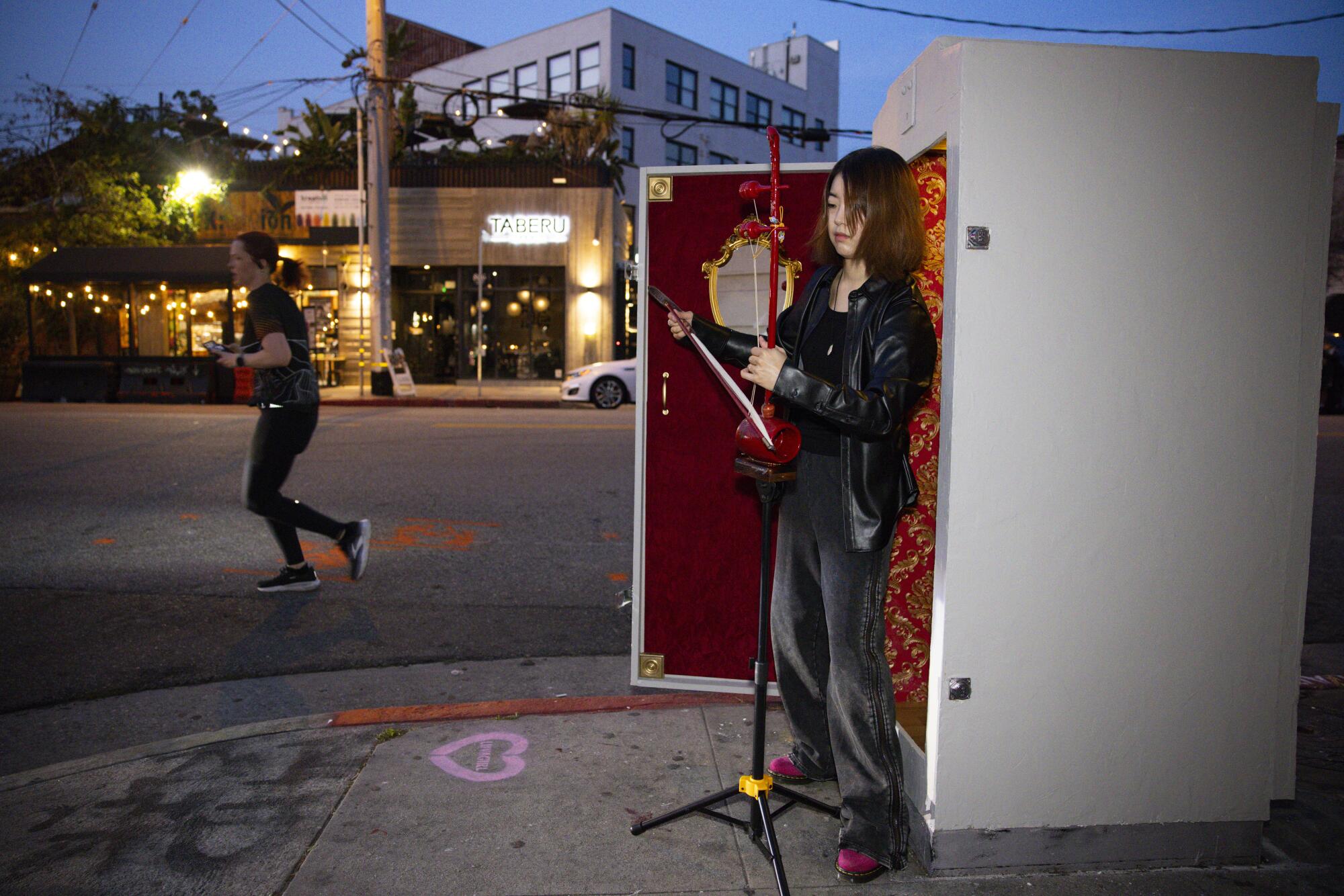 Musician Jeonghyeon Joo, 31, plays the haegeum outside of S.C. Mero's latest art project, a theater in a faux electrical box.